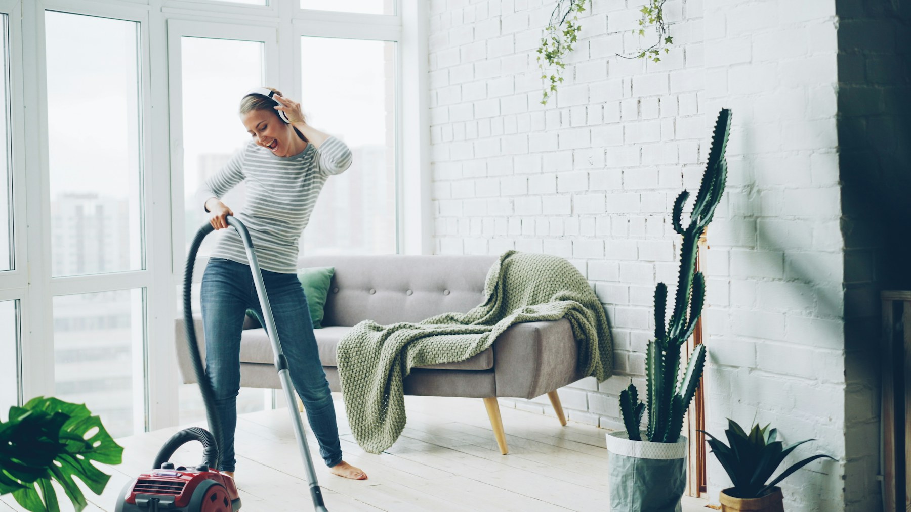 A bright living room being carefully vacuumed